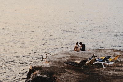 坐在海边悬崖上的男人和女人和日光浴者